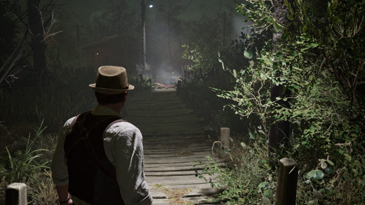 Mężczyzna w kapeluszu stoi na drewnianym moście w mrocznym, mglistym lesie patrząc w kierunku słabo oświetlonej ścieżki.