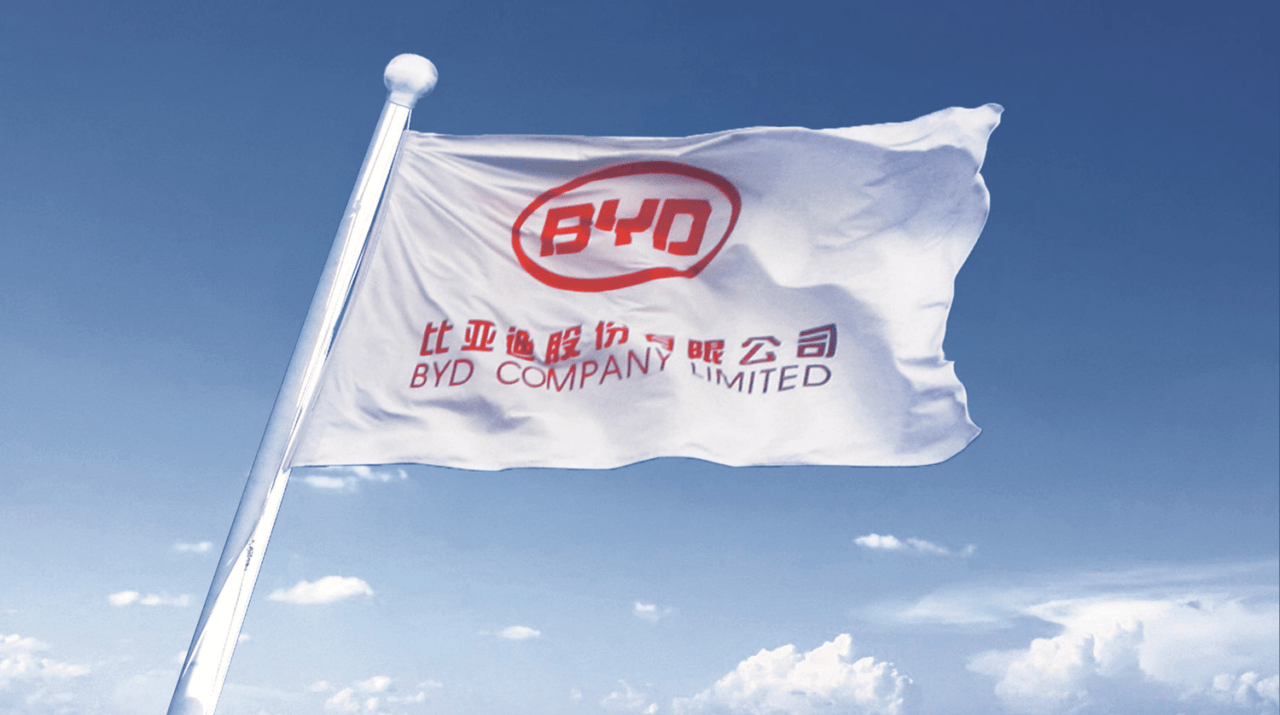 Flaga z logo i napisami w języku chińskim, rozwiewana na wietrze, na tle niebieskiego nieba z chmurami.