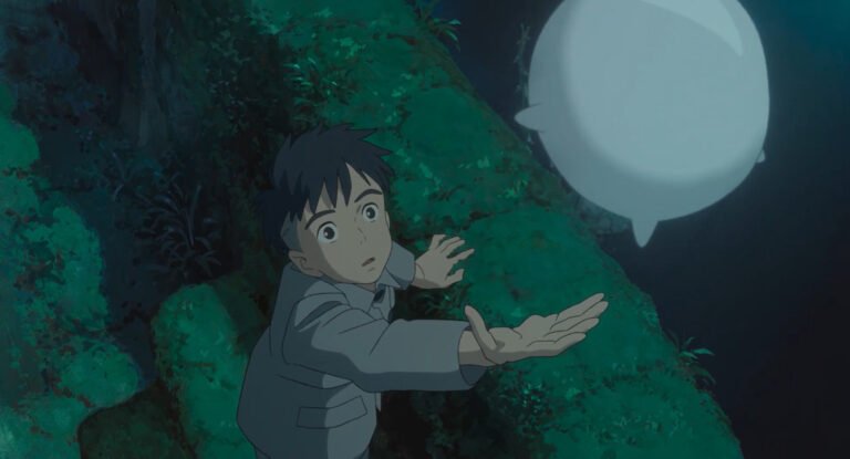 Kadr z filmu Chłopiec i czapla. Animowana postać chłopca w szarym mundurku z zaskoczonym wyrazem twarzy, wyciągającego ręce w stronę białej, świetlnej kuli na tle nocnego lasu.