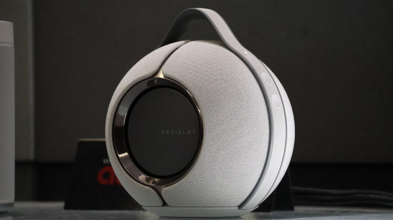 Głośnik bezprzewodowy Devialet Phantom umieszczony na blacie, z białą obudową i centralnym elementem w kolorze czarnym.