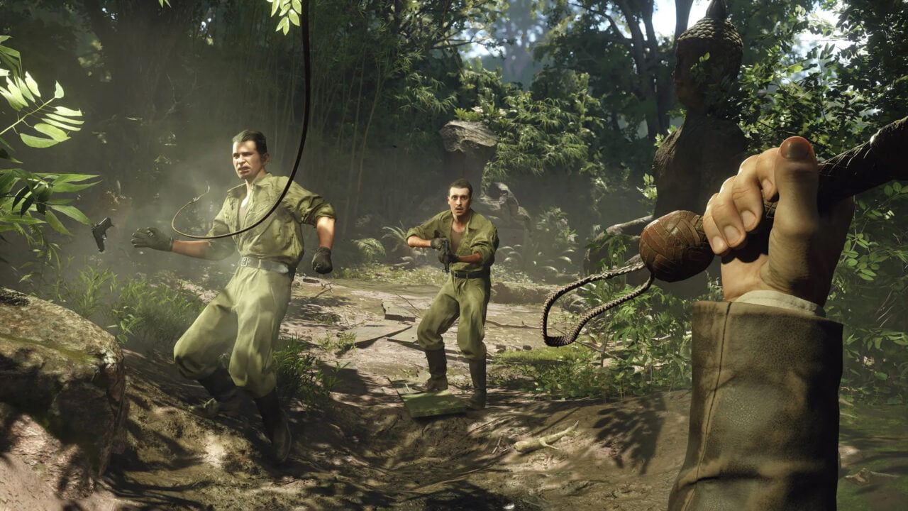 Kadr z gry Indiana Jones i Wielki krąg. Trzej żołnierze w dżungli, jeden wymachuje maczetą, dwaj inni celują z broni, w tle posąg Buddy.