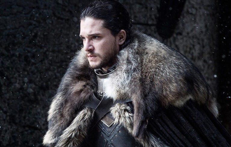Kit Harnigton jako Jon Snow w serialu Gra o Tron. Mężczyzna w średniowiecznym stroju z futrzanym płaszczem stoi podczas padającego śniegu.