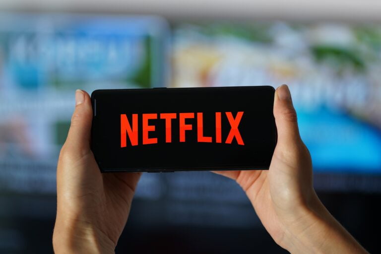 Osoba trzymająca telefon z wyświetlonym logo Netflix.