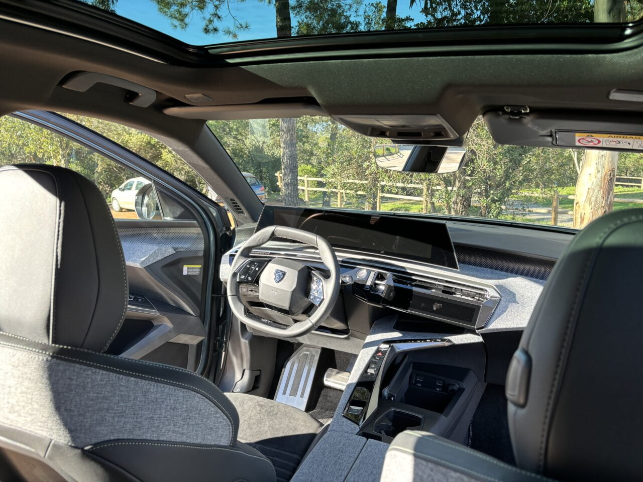 Wnętrze nowoczesnego samochodu z widokiem na kierownicę, deski rozdzielczej z ekranem dotykowym i wygodne, tapicerowane siedzenia.