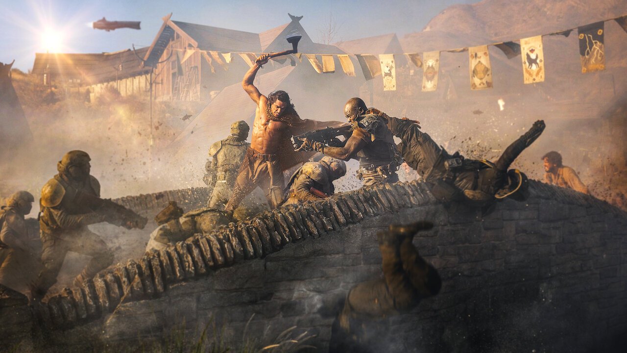 Scena walki z mężczyzną w centrum, który broni się przy użyciu kości dinozaura, otoczony przez innych walczących w postapokaliptycznych strojach na tle rozbitej wioski i latającego statku powietrznego.
