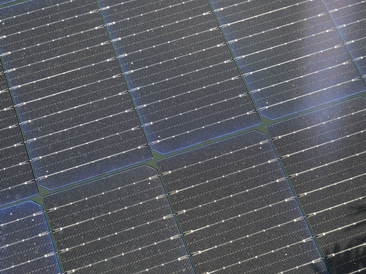 Panele słoneczne pokryte siecią cienkich linii, widoczne z bliskiej perspektywy, pod kątem, z odzwierciedleniem światła słonecznego.
