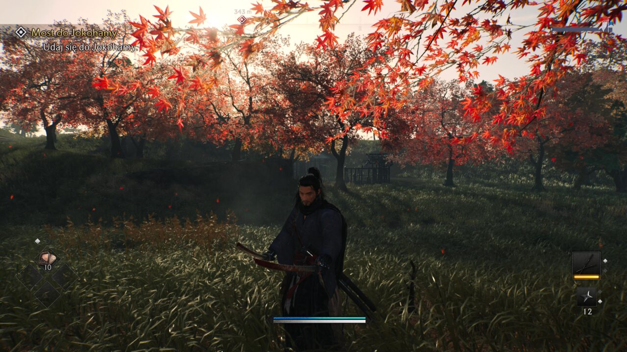 Recenzja Rise of the Ronin na PS5. Postać z gry wideo w średniowiecznym ubiorze stoi na trawiastej polanie otoczonej przez czerwone liście drzew, z paskiem stanu i elementami interfejsu użytkownika widocznymi na ekranie.
