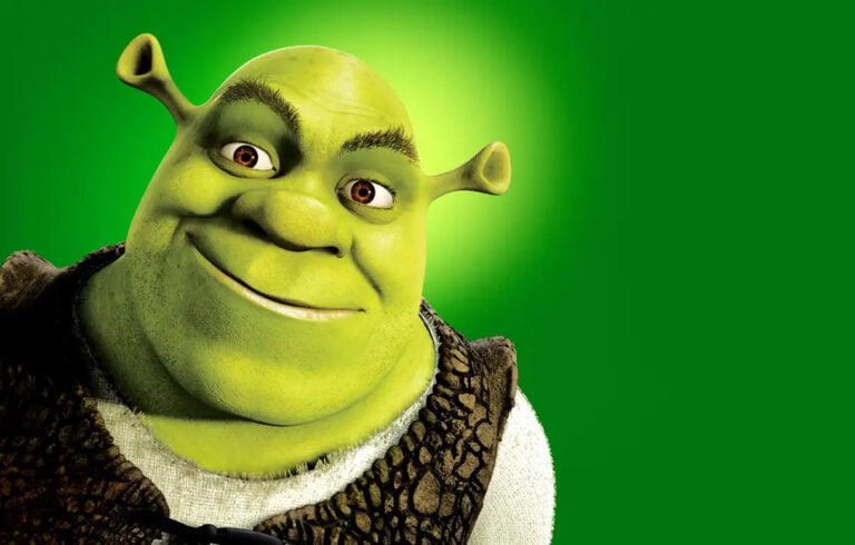 Shrek o zielonej skórze z uszami przypominającymi róg ślimaka, ubrana w średniowieczne ubranie, z uśmiechem na tle zielonego ekranu.