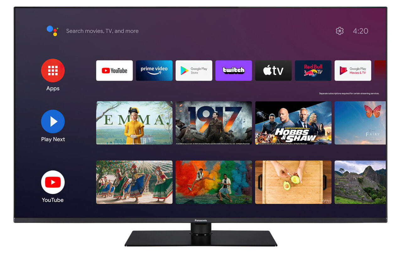 Telewizor wyświetlający interfejs inteligentnego systemu, z ikonami aplikacji i miniaturami filmów oraz programów telewizyjnych na ekranie.