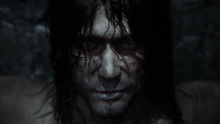 Kadr ze zwiastuna gry Thorgal. Portret mężczyzny z rozmazaną krwią na twarzy, o intensywnym wzroku, z mokrymi, przylegającymi do skóry włosami, na ciemnym, nieostrym tle.