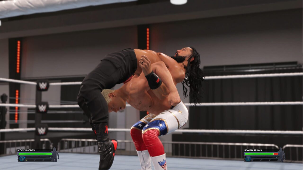 Wrestlerzy w ringu podczas walki – jeden wykonuje ruch podnoszenia przeciwnika do góry nogami.
