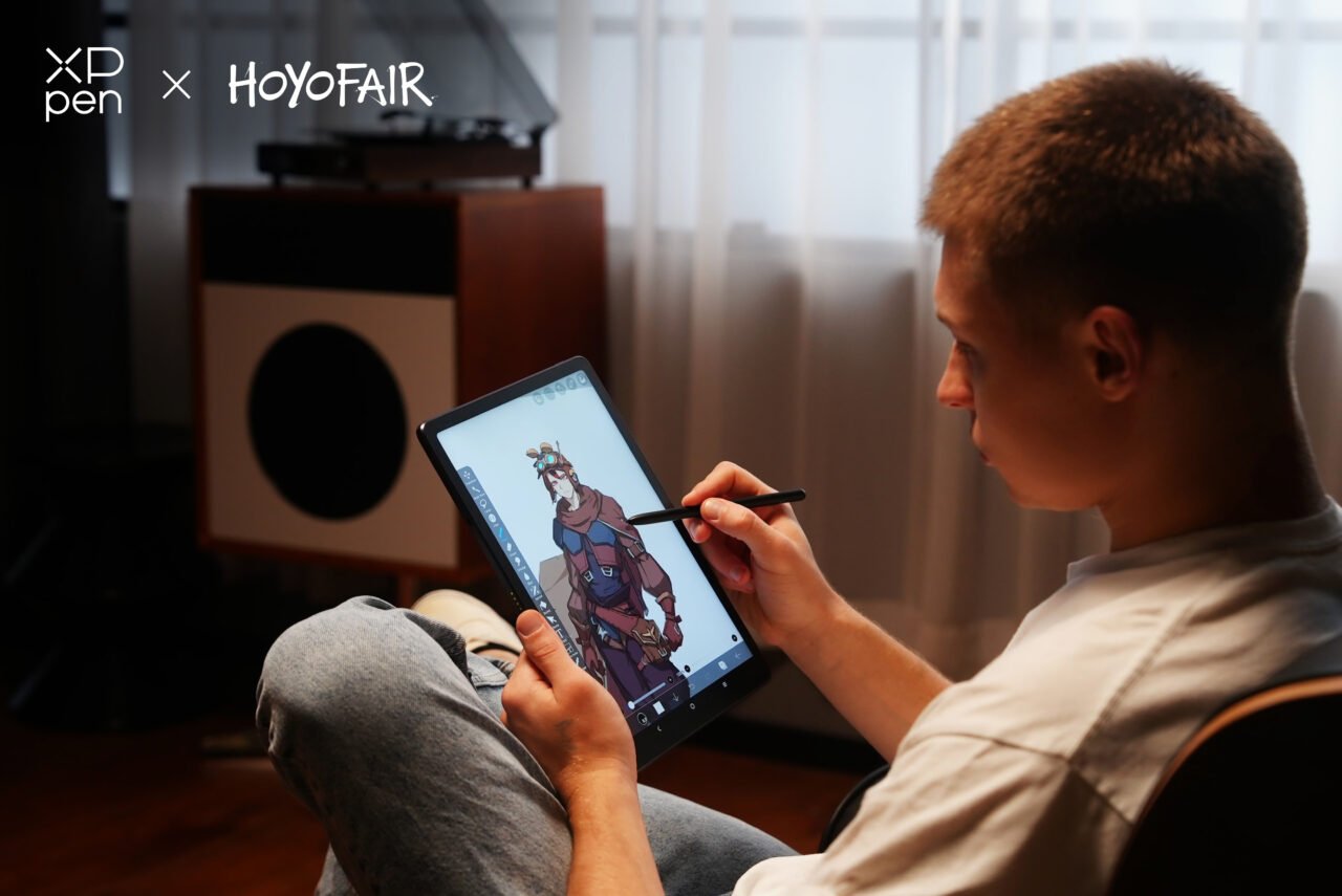 Osoba siedząca bokiem rysuje na cyfrowym tablecie XPPen z użyciem piórka, na ekranie tabletu widoczna jest kolorowa postać komiksowa.