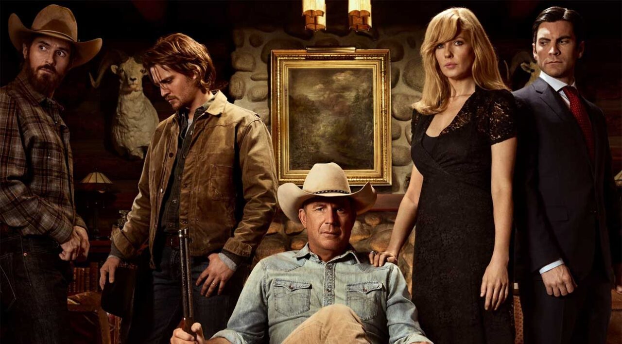 Gdzie obejrzeć serial Yellowstone. Grupa pięciu osób w stylu kowbojskim z dobytkiem w tle; na pierwszym planie mężczyzna w kapeluszu kowbojskim siedzący na krześle.