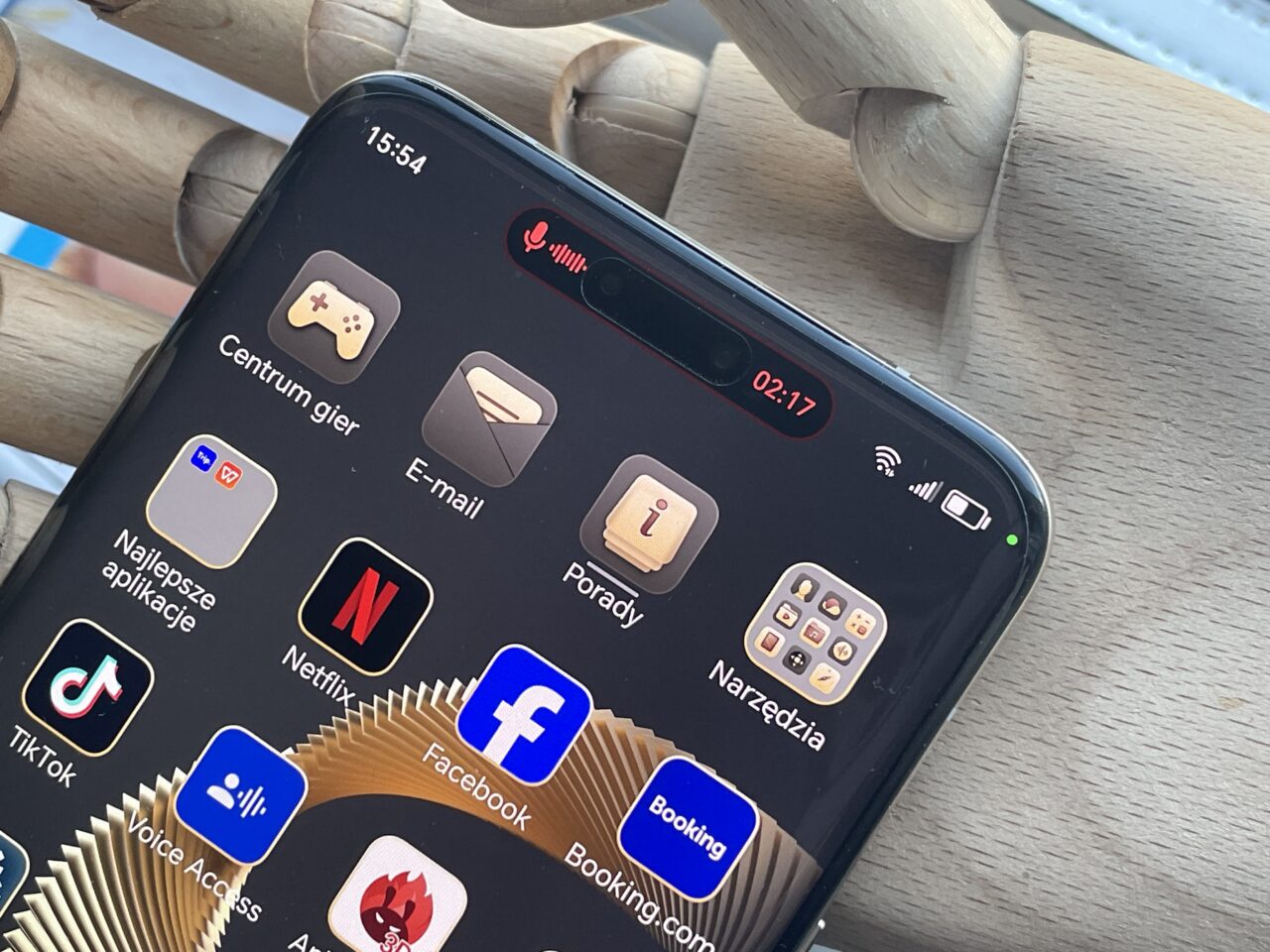 Smartfon z ekranem pokazującym kolorowe ikony aplikacji, takie jak Centrum gier, E-mail, Netflix, Facebook, TikTok i inne, z zaznaczonym górnym paskiem stanu o godzinie 15:34, poziomem baterii oraz połączeniem Wi-Fi i sygnałem sieci komórkowej.