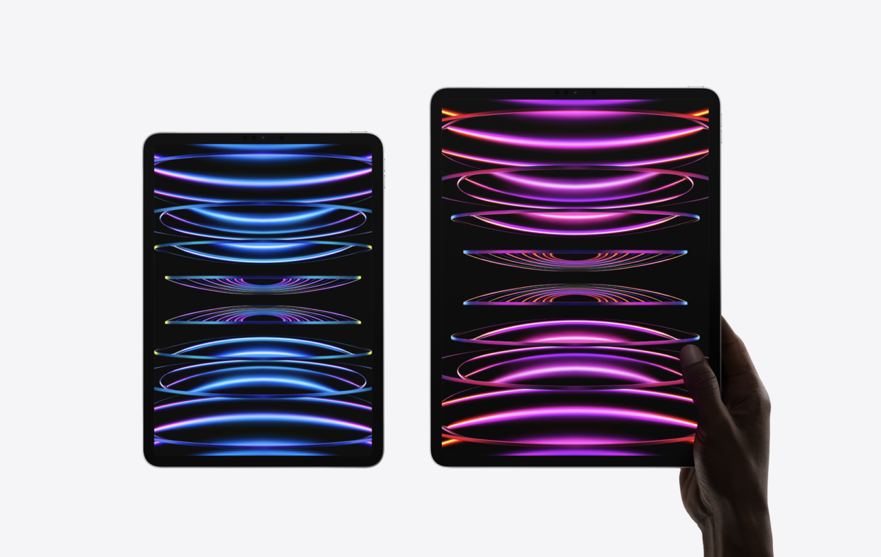 Nowości od Apple. Dłoń trzymająca tablet z kolorowymi abstrakcyjnymi grafikami, obok mniejszy tablet z tymi samymi grafikami.