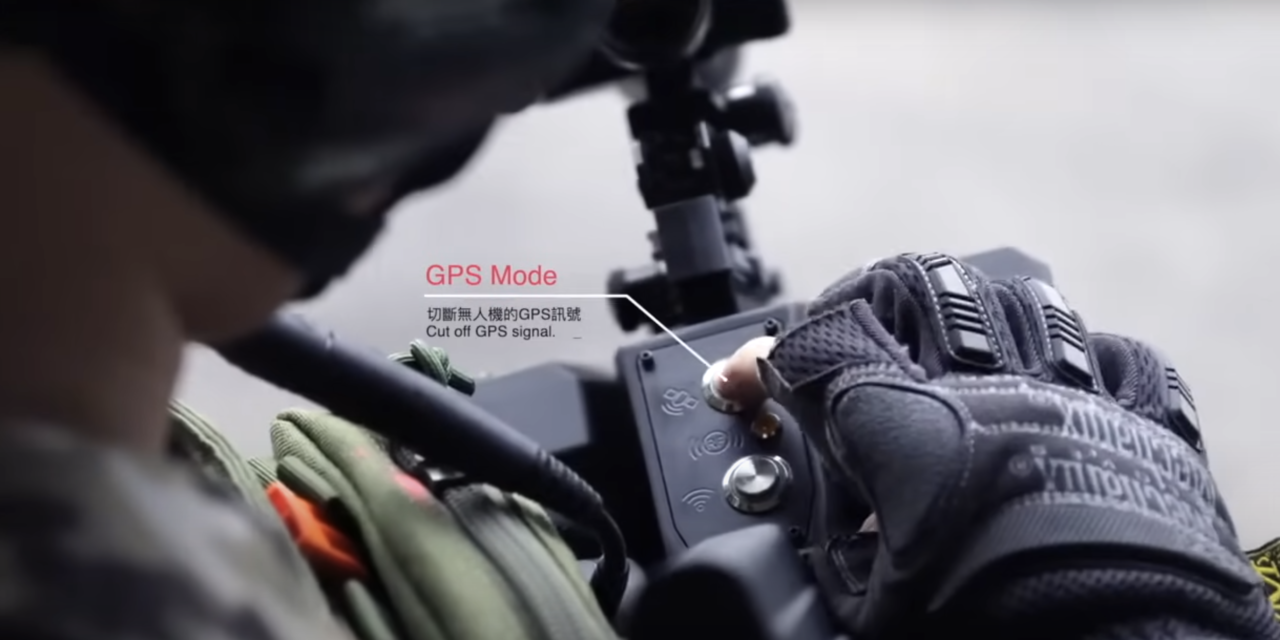 Zabójca dronów Skynet. Osoba w taktycznych rękawicach operuje urządzeniem z wyświetlaczem i napisami "GPS Mode" oraz "Cut off GPS signal" w tle.