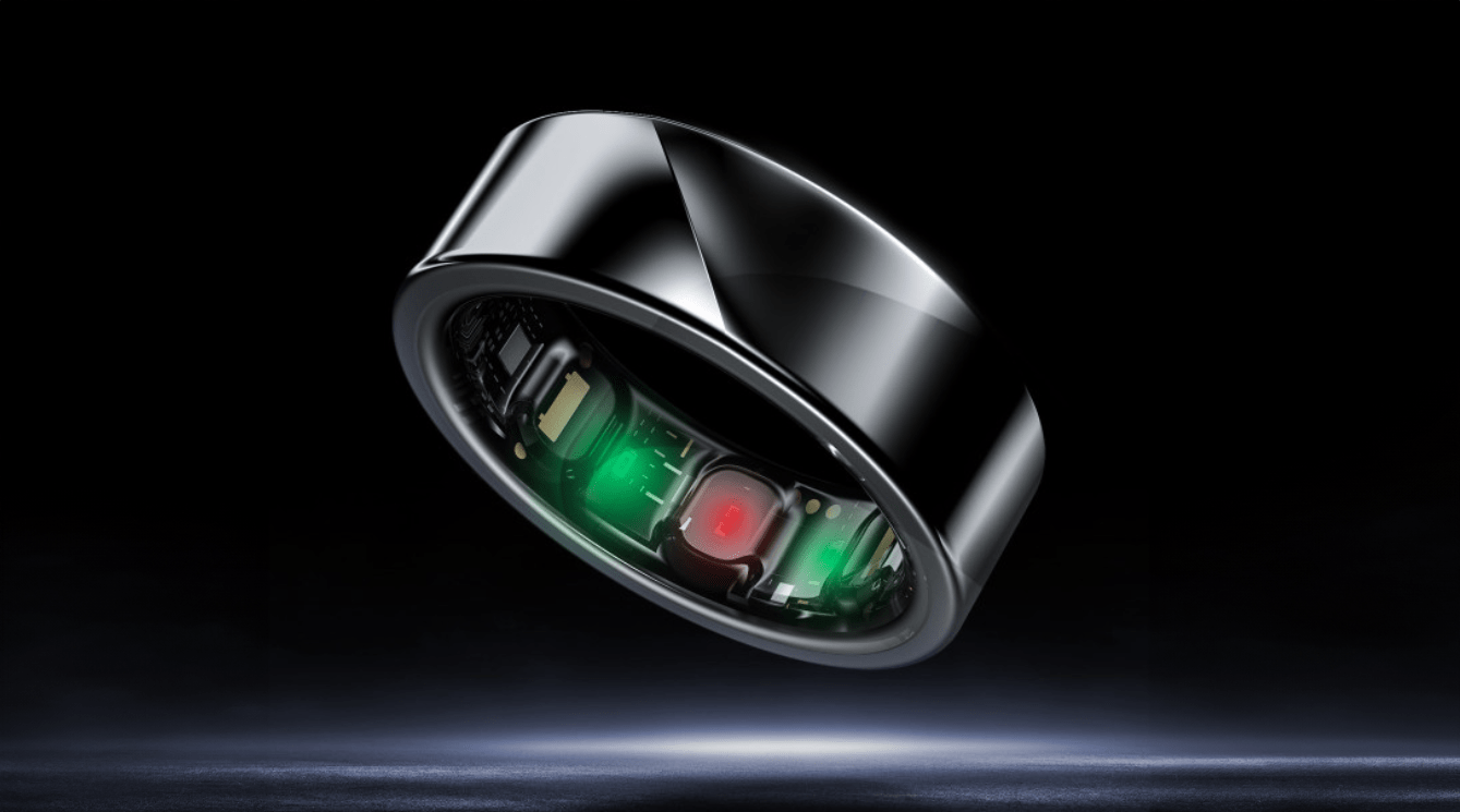 Pierścień inteligentny z elektronicznymi komponentami widocznymi pod przezroczystą powierzchnią, unosi się na czarnym tle z delikatnym oświetleniem akcentującym jego błyszczącą powierzchnię.
