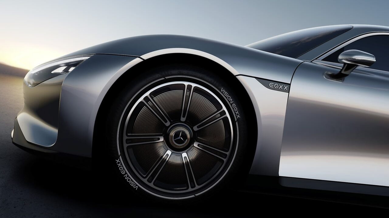 Zbliżenie na srebrny samochód elektryczny Mercedes-Benz EQXX z akcentem na aerodynamicznym przednim błotniku i designerskim kole.