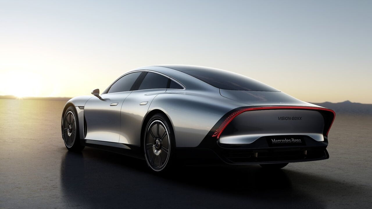 Elektryk srebrzysty samochód koncepcyjny Mercedes-Benz EQXX widziany z tyłu na tle zachodzącego słońca i horyzontu.