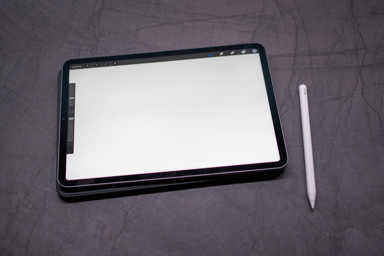 Tablet graficzny z białym ekranem i rysikiem na ciemnoszarym tle. Aplikacje do rysowania bywają na nim uruchomione. 