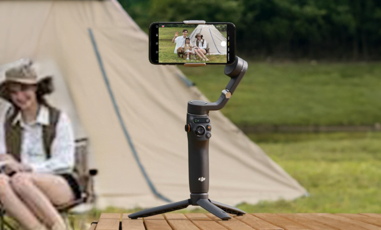 Gimbal do telefonu ze smartfonem, który wyświetla zdjęcie dwóch osób pozujących na tle namiotu.