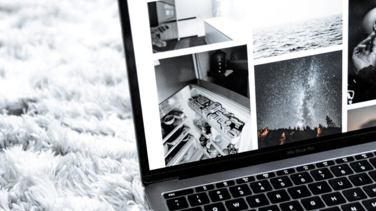 Laptop MacBook Pro na białym, puszystym dywanie z otwartym interfejsem programu do obróbki zdjęć, wyświetlającym czarno-białe fotografie, w tym zdjęcia morza, nocnego nieba i innych przedmiotów.
