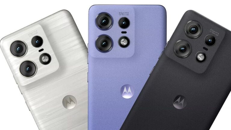 Trzy telefony komórkowe marki Motorola ułożone obok siebie, z widocznymi tylnymi aparatami fotograficznymi, w kolorach: białym, fioletowym i czarnym.