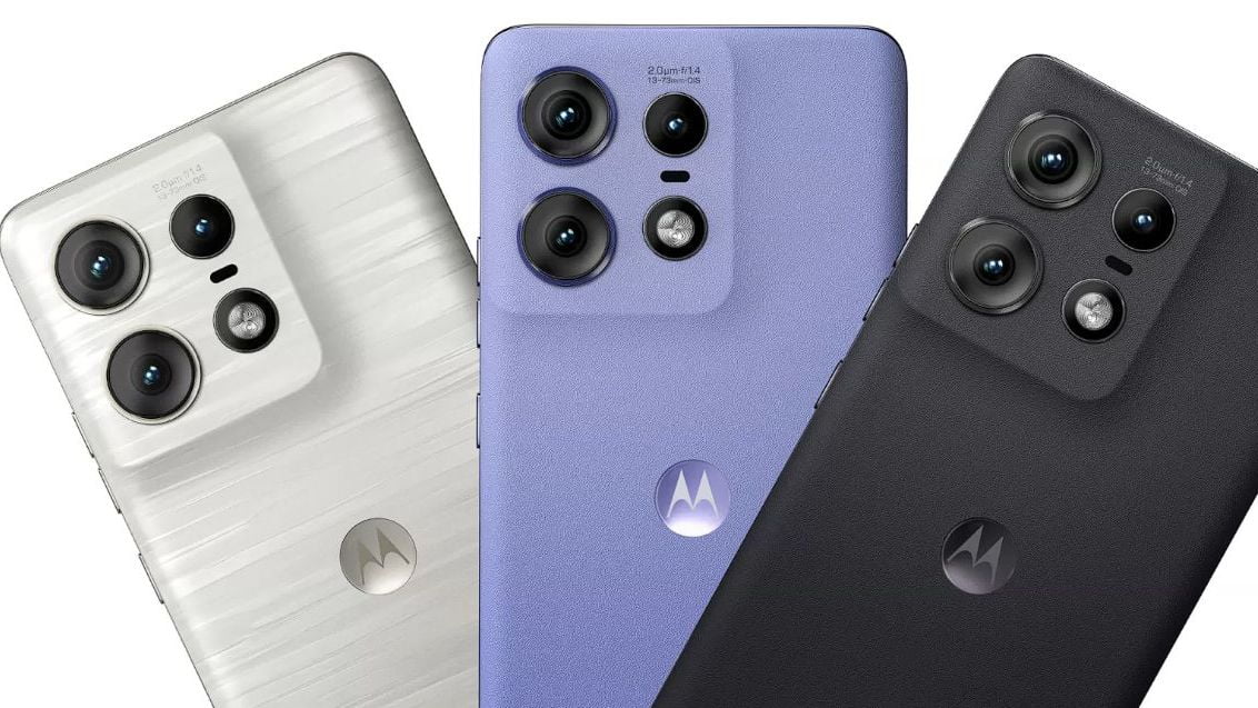 Trzy telefony komórkowe marki Motorola ułożone obok siebie, z widocznymi tylnymi aparatami fotograficznymi, w kolorach: białym, fioletowym i czarnym.