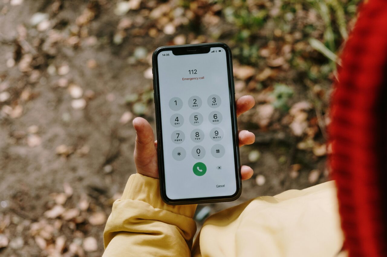 Advanced Mobile Location. Osoba trzymająca smartfon z wyświetlonym ekranem wybierania numeru alarmowego 112.