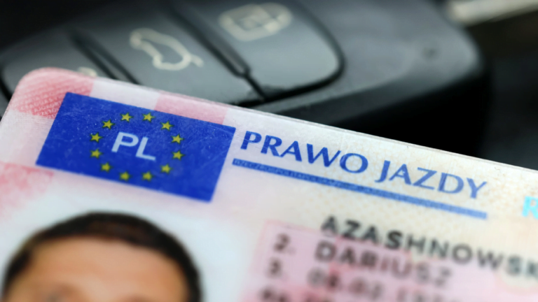 Polskie prawo jazdy z widocznym fragmentem zdjęcia osoby i nazwisko, na tle kluczy samochodowych.