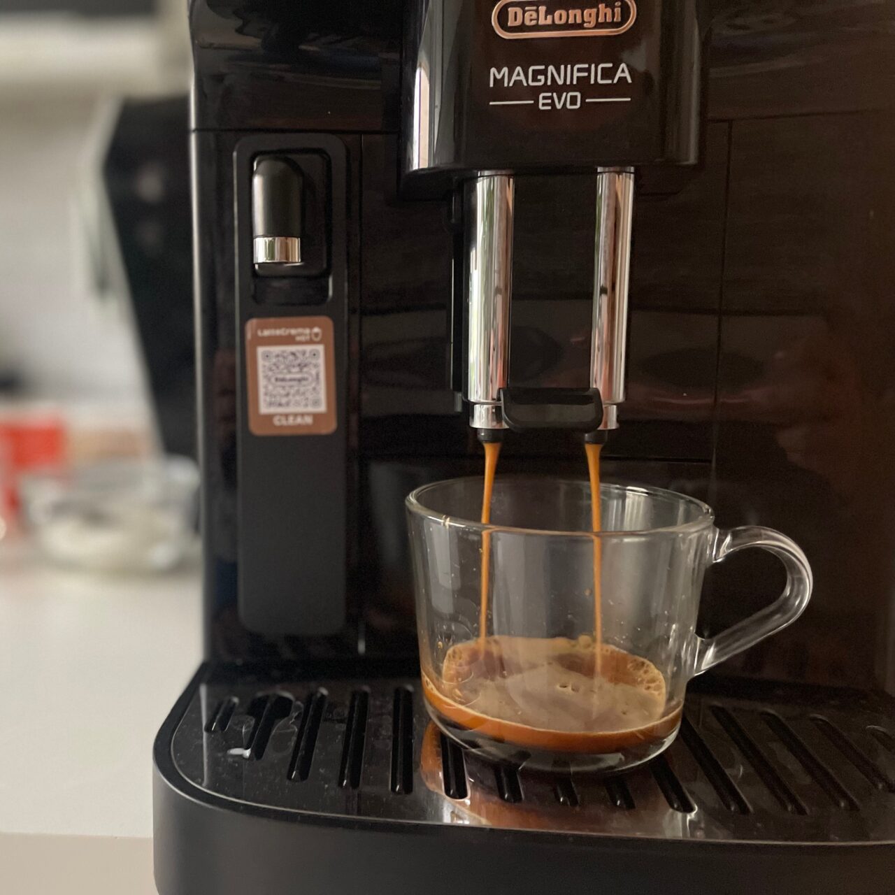 Ekspres do kawy De'Longhi Magnifica EVO nalewający espresso do przezroczystej filiżanki.