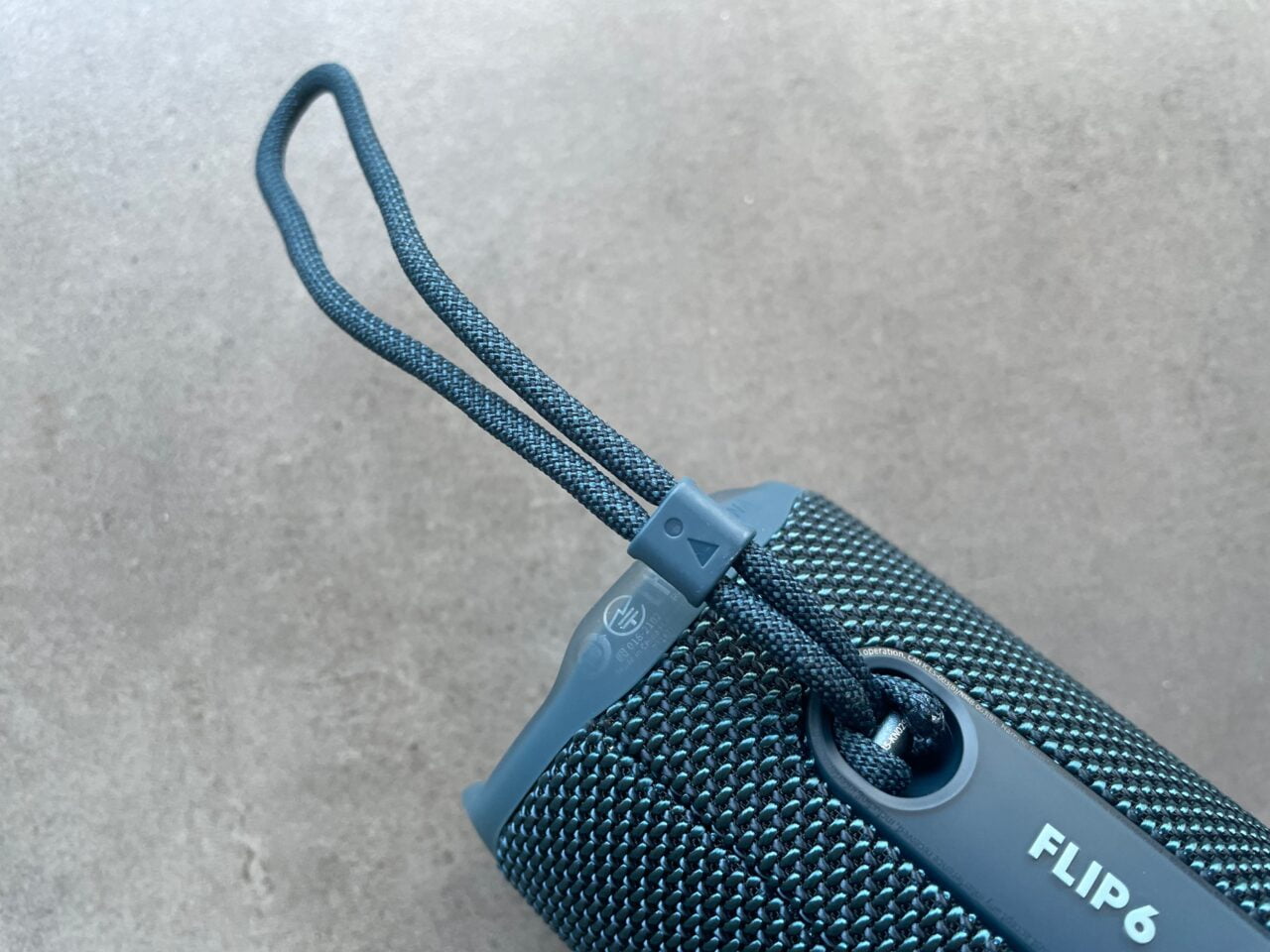 Przenośny głośnik Bluetooth w niebieskim kolorze z pętelką uchwytu i widocznym napisem "FLIP 6".