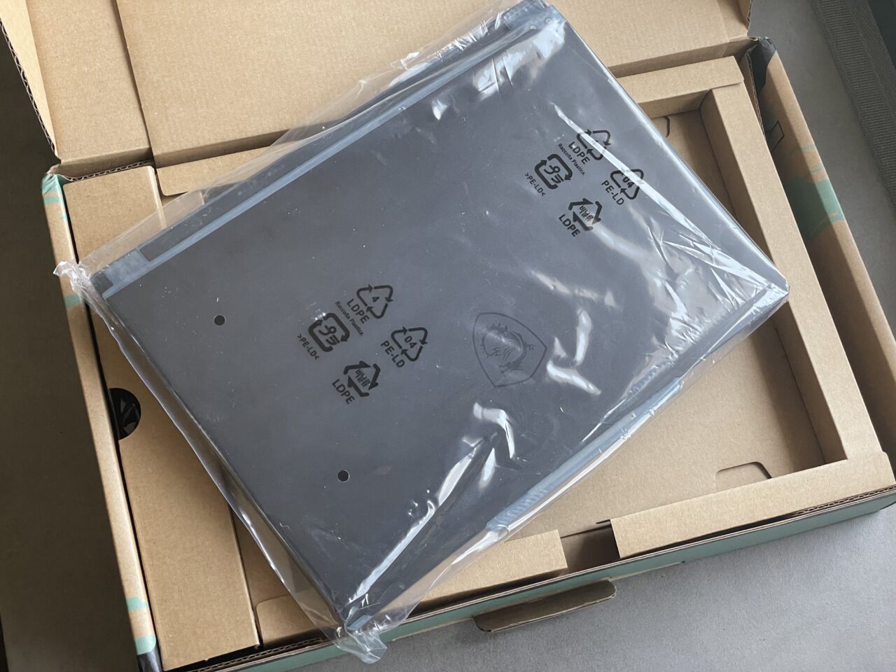 Laptop opakowany w folię ochronną umieszczony w kartonowym pudełku.