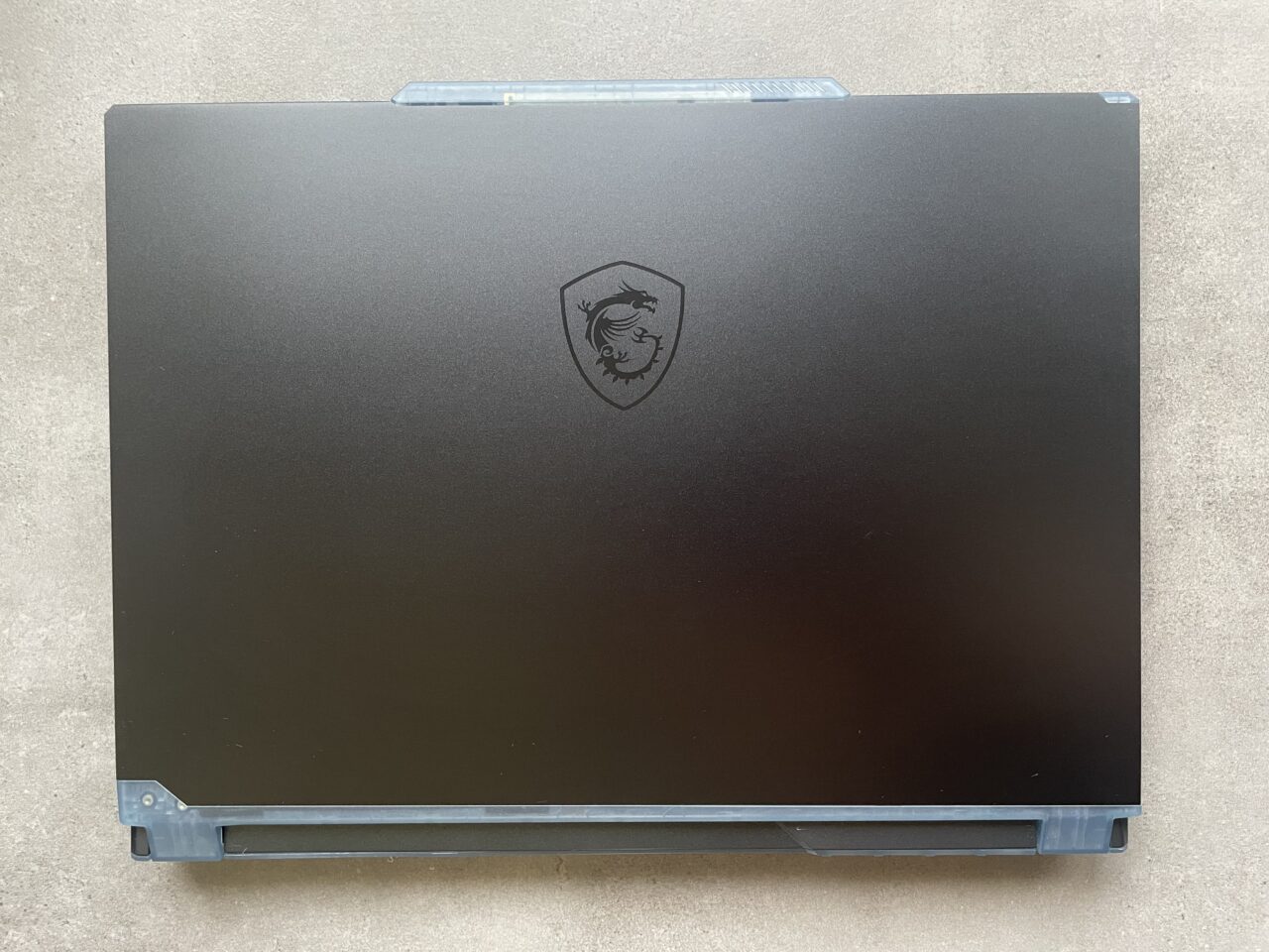 Czarny laptop gamingowy z zamkniętą pokrywą i widocznym logo w kształcie tarczy z głową lwa.