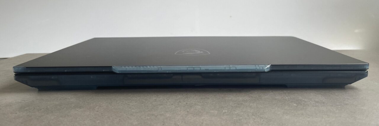 Zamknięty czarny laptop na jasnoszarym tle, z widocznym logo na pokrywie.