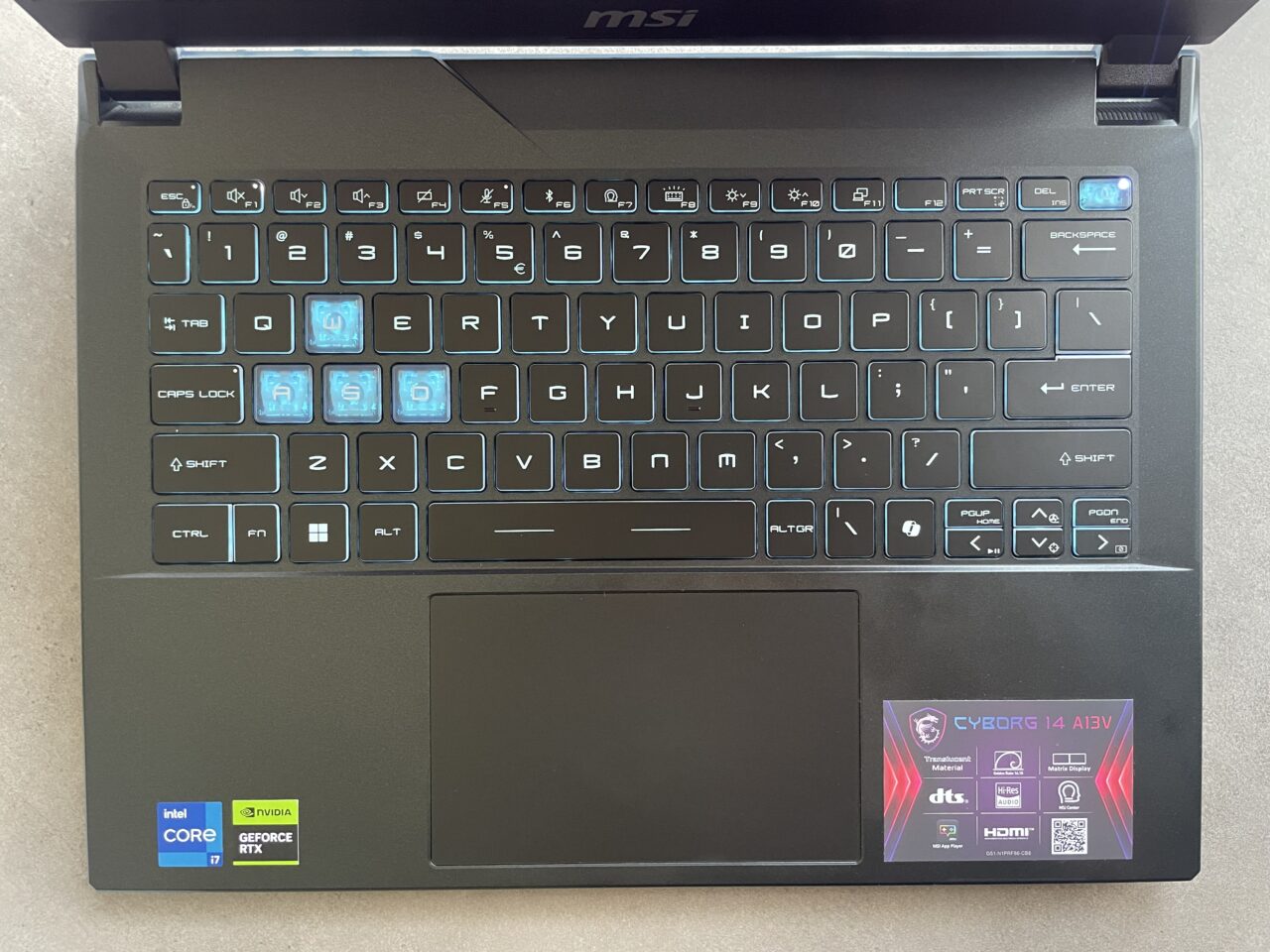 Klawiatura laptopa marki MSI z podświetlonymi klawiszami i naklejkami informacyjnymi o komponentach Intela i Nvidii oraz etykietą modelu CYBORG 14 A13V w dolnym prawym rogu.