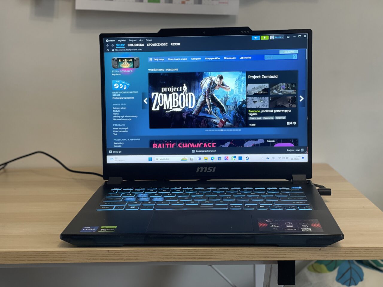 Laptop gamingowy MSI na biurku z włączoną stroną platformy dystrybucji gier Steam w przeglądarce internetowej.