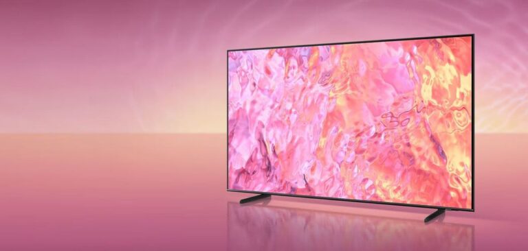 Telewizor z płaskim ekranem wyświetlający abstrakcyjny obraz w odcieniach różu i pomarańczu, ustawiony na jednolitym tle w kolorze różowym.