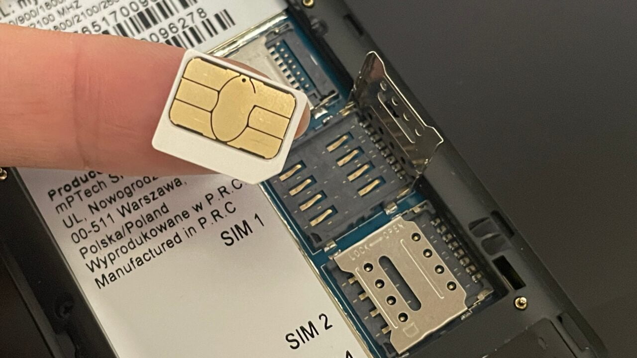 Osoba wkłada kartę SIM do wnęki w telefonie komórkowym z dwoma gniazdami kart SIM.