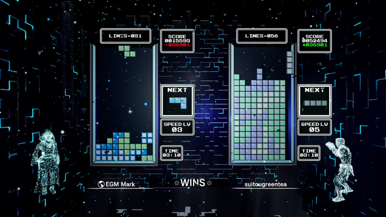 Grafika przedstawia ekran gry komputerowej wzorowanej na Tetris, z dwoma polami gry oraz holograficznymi postaciami po obu stronach ekranu. Na lewo znajduje się pole z napisem "LINES-081" i wynikiem "016598", po prawej widnieje drugie pole z "LINES-056" i wynikiem "052494". W centralnej części obrazu wyświetlone są słowa "EGM Mark" i "suitougreentea", zdaje się to być identyfikatory graczy, a pomiędzy nimi znajduje się wynik "0 WINS". Obie plansze zawierają klocki Tetris w różnych konfiguracjach, a obok każdej wyświetlany jest kolejny spadający klocek i aktualny poziom prędkości. Na górze plansz znajdują się dwa zegary pokazujące czas 03:10. Tło ekranu to kosmiczna sceneria z cyfrowymi elementami. Tetris Effect: Connected to prawdziwy następca Tetrisa
