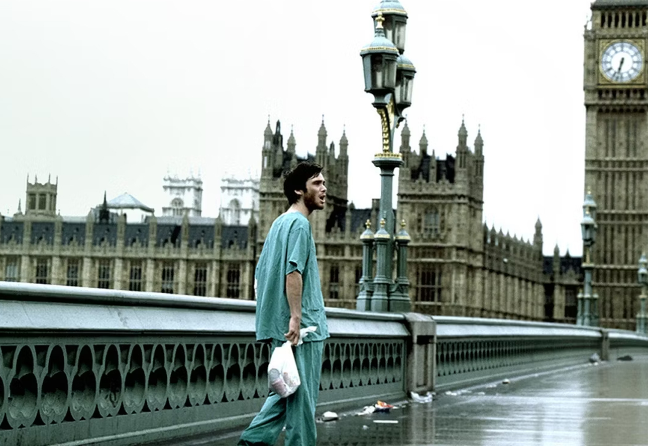 Kadr z filmu 28 dni później. Mężczyzna w szpitalnej pidżamie idzie po mokrym moście z widokiem na Big Ben i Westminsterski Pałac.
