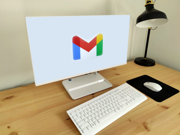 Biurko z komputerem wyświetlającym logo Gmaila, klawiaturą, myszką i lampką.