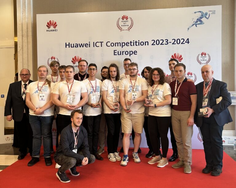 Grupa osób z identyfikatorami i statuetkami stojąca przed banerem "Huawei ICT Competition 2023-2024 Europe".
