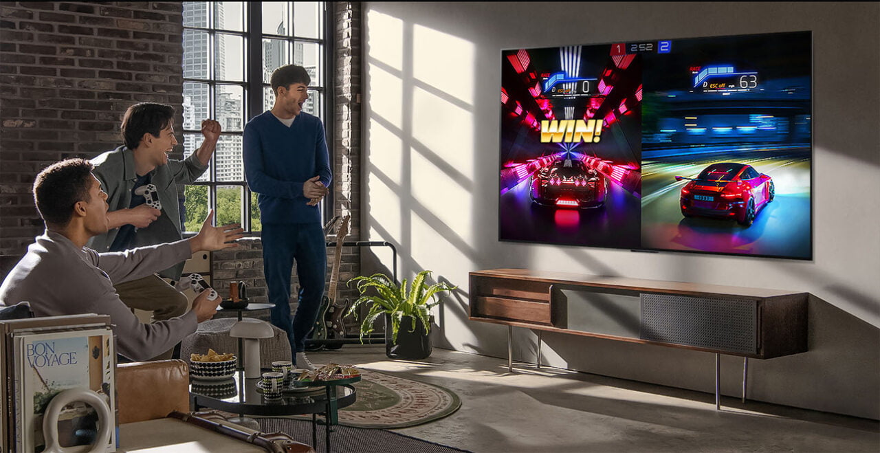 Czterej mężczyźni grający w gry wideo na dużym ekranie w nowoczesnym salonie.