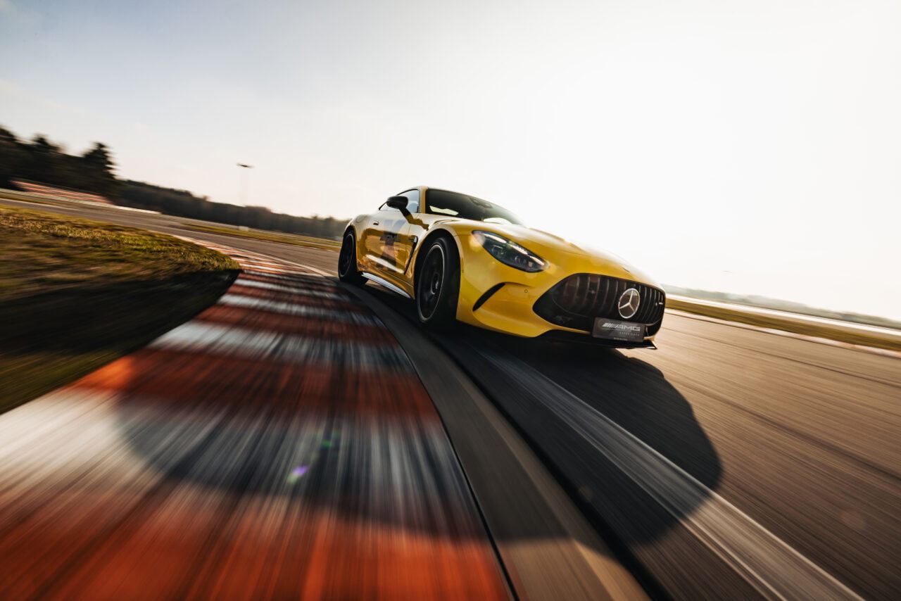 Żółty samochód sportowy marki Mercedes AMG jedzie z dużą prędkością na torze wyścigowym.