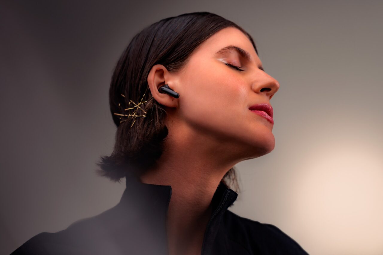 Kobieta z zamkniętymi oczami, słuchająca muzyki na bezprzewodowych słuchawkach dousznych.