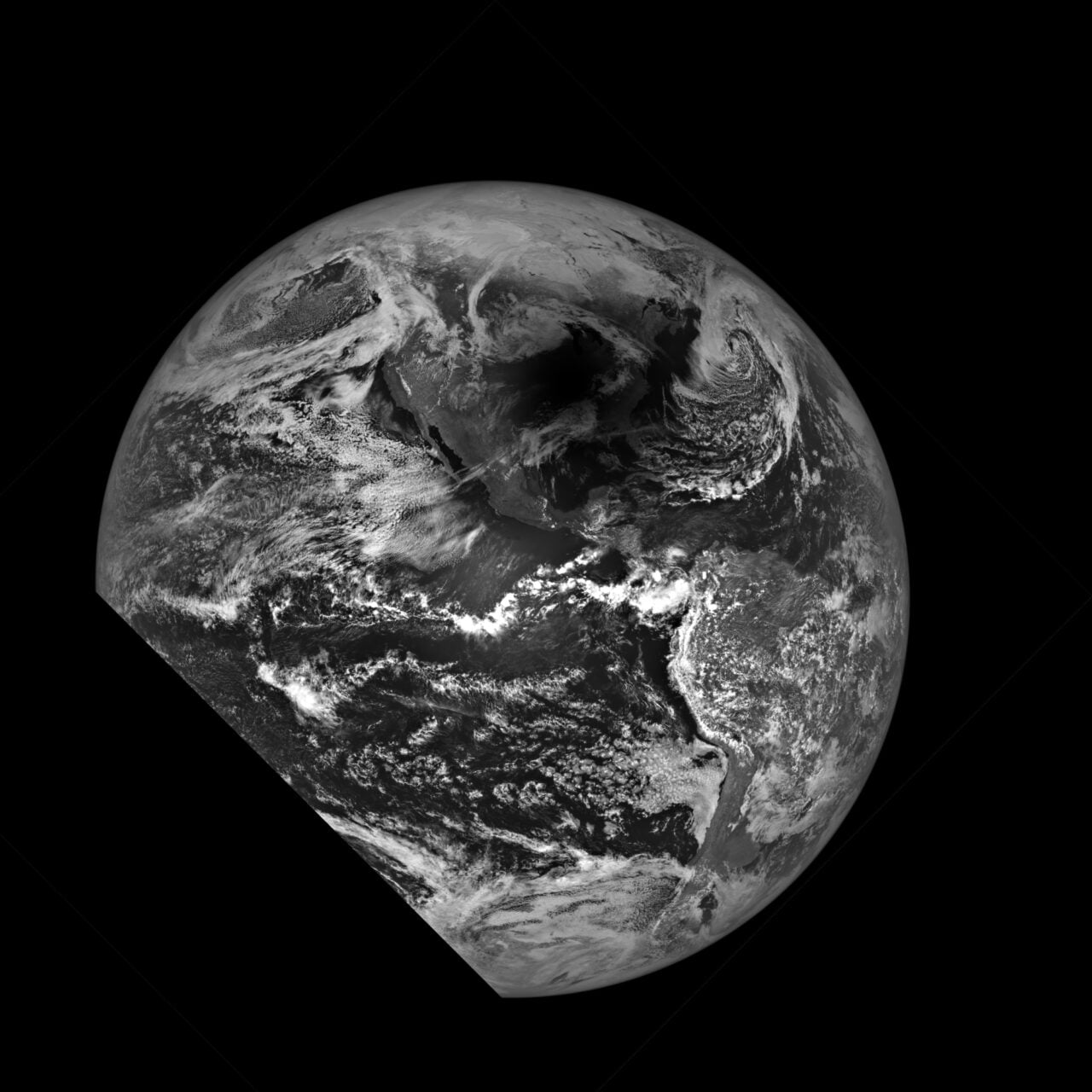 Zdjęcie satelitarne Ziemi przedstawiające zaćmienie Słońca wykonane przez NASA w czerni i bieli ukazujące fragment planety z widocznymi chmurami i kontynentami.