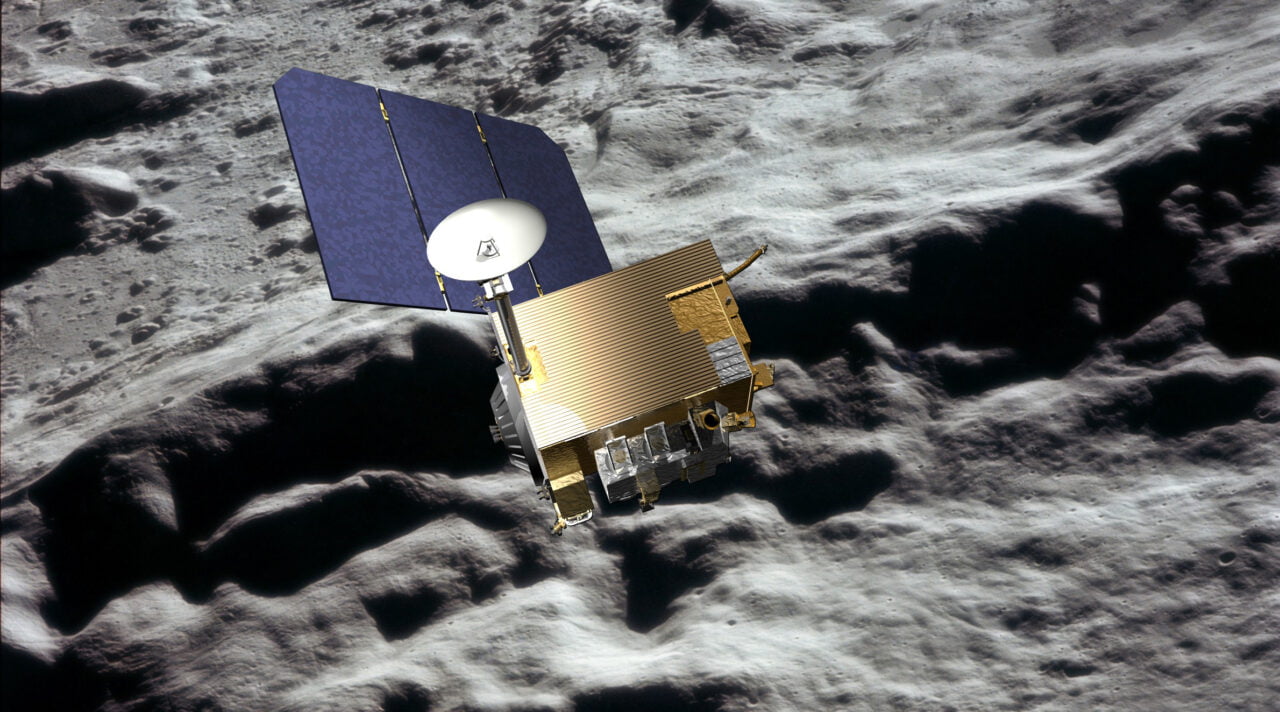 Satelita na orbicie wokółksiężycowej, z panelem słonecznym i złotą izolacją termiczną, na tle nierównego terenu Księżyca.