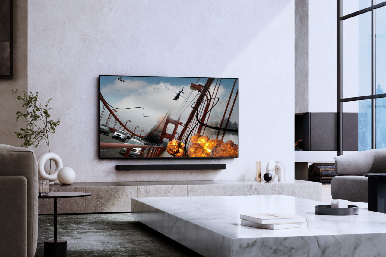 Nowoczesny salon z dużym telewizorem Sony BRAVIA 9 zawieszonym na ścianie wyświetlającym kadr z filmu akcji. Telewizory Sony z nowym trybem wyświetlania.