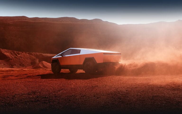 Pikap o futurystycznym designie poruszający się po pustynnym terenie z unoszącym się kurzem w tle.